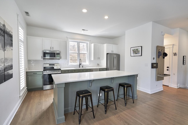 1501 W Diversey Pkwy Unit B, Chicago, IL 60614 - kitchen with stainless steel appliances, wood finished floors, a breakfast bar area, light countertops, and backsplash