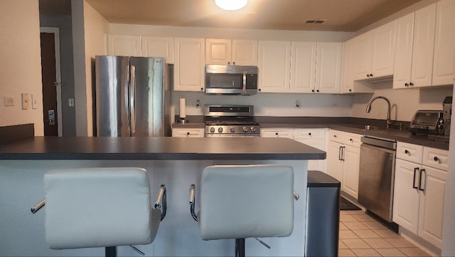875 E 22nd St Unit 204, Lombard, IL 60148 - kitchen featuring appliances with stainless steel finishes, dark countertops, white cabinets, and a kitchen bar