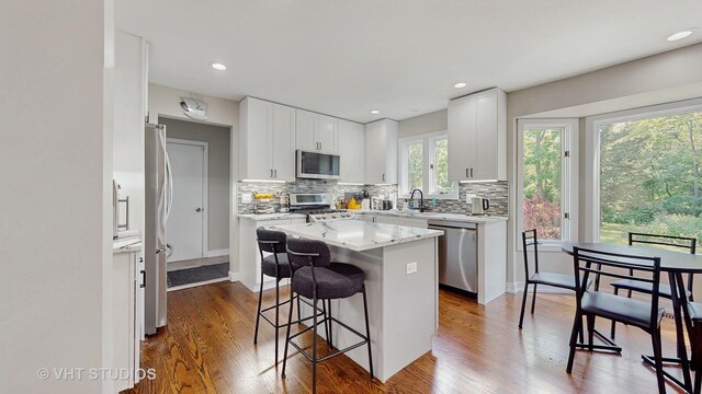 3425 Woodlawn Ave, Gurnee, IL 60031 - kitchen with stainless steel appliances, a kitchen breakfast bar, a center island, decorative backsplash, and dark wood finished floors
