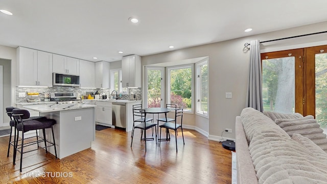 3425 Woodlawn Ave, Gurnee, IL 60031 - kitchen with appliances with stainless steel finishes, backsplash, a breakfast bar, wood finished floors, and white cabinets