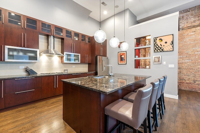 2411 W Walton St Unit 2B, Chicago, IL 60622 - kitchen featuring wall chimney range hood, freestanding refrigerator, dark wood-type flooring, a kitchen island with sink, and a breakfast bar area