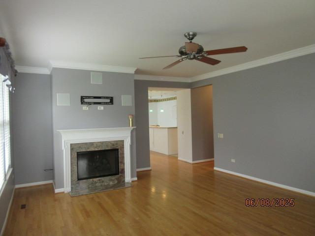 13005 Big Horn Dr, Huntley, IL 60142 - unfurnished living room featuring ceiling fan, wood finished floors, crown molding, a fireplace with flush hearth, and plenty of natural light