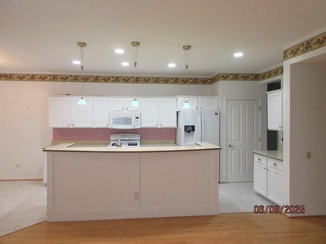 13005 Big Horn Dr, Huntley, IL 60142 - kitchen featuring white appliances, white cabinetry, tasteful backsplash, decorative light fixtures, and a center island