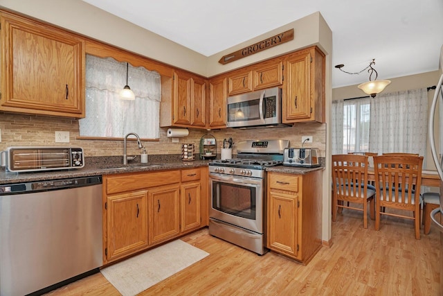 512 Creekside Cir, Minooka, IL 60447 - kitchen with stainless steel appliances, light wood finished floors, dark countertops, decorative backsplash, and brown cabinets