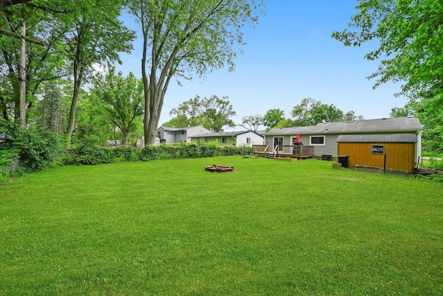 9111 Memory Trl, Wonder Lake, IL 60097 - view of green lawn featuring a deck, an outbuilding, and an outdoor fire pit