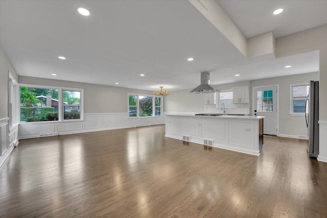 3935 W Jarvis Ave, Lincolnwood, IL 60712 - unfurnished living room with a chandelier, plenty of natural light, wood finished floors, a wainscoted wall, and recessed lighting