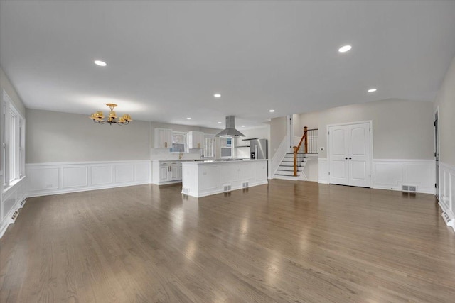 3935 W Jarvis Ave, Lincolnwood, IL 60712 - unfurnished living room featuring a chandelier, a wainscoted wall, stairway, wood finished floors, and recessed lighting