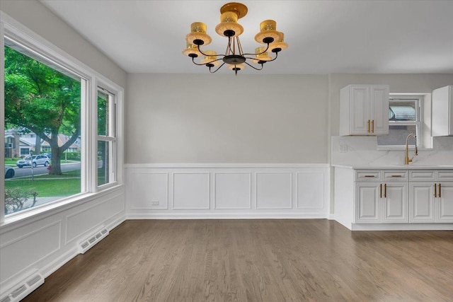 3935 W Jarvis Ave, Lincolnwood, IL 60712 - unfurnished dining area featuring plenty of natural light, a chandelier, wood finished floors, wainscoting, and a decorative wall