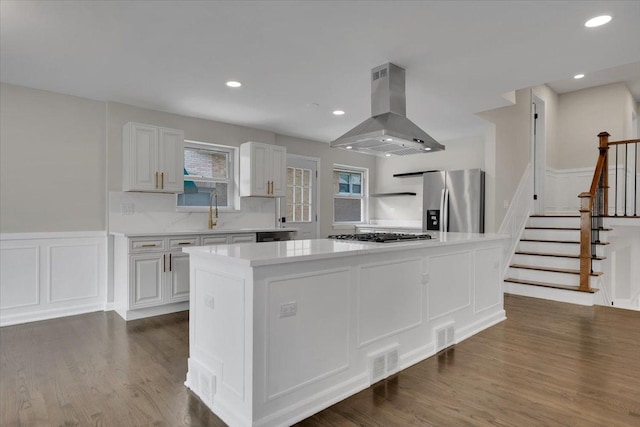 3935 W Jarvis Ave, Lincolnwood, IL 60712 - kitchen with island exhaust hood, appliances with stainless steel finishes, a decorative wall, light countertops, and dark wood-type flooring