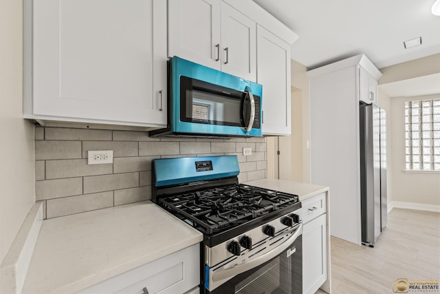 8207 S Laflin St, Chicago, IL 60620 - kitchen with stainless steel appliances, white cabinetry, backsplash, and light wood-style flooring