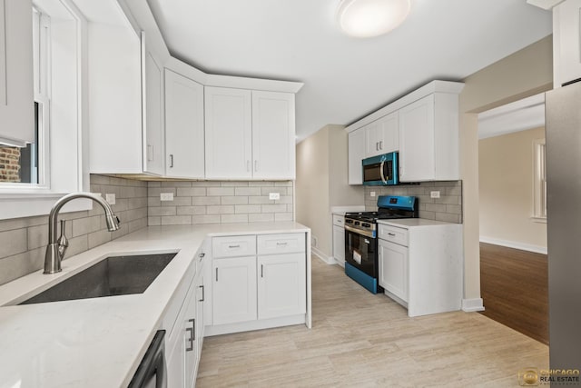 8207 S Laflin St, Chicago, IL 60620 - kitchen featuring stainless steel appliances, white cabinetry, light wood-style floors, decorative backsplash, and light stone counters