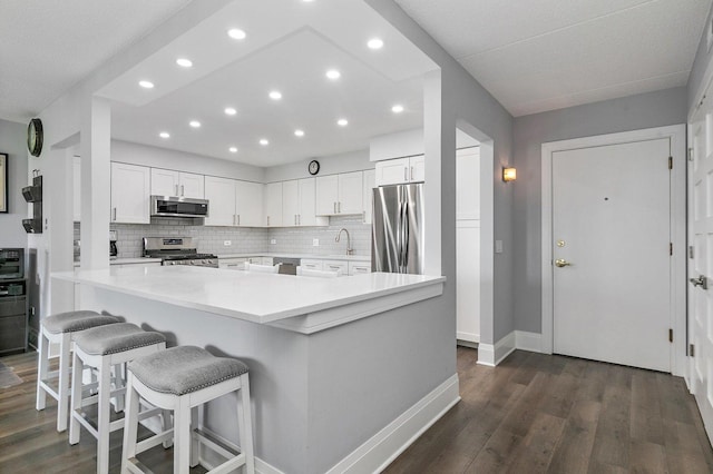 4210 N Natchez Ave Unit 208, Chicago, IL 60634 - kitchen featuring appliances with stainless steel finishes, recessed lighting, dark wood-type flooring, white cabinets, and a breakfast bar area