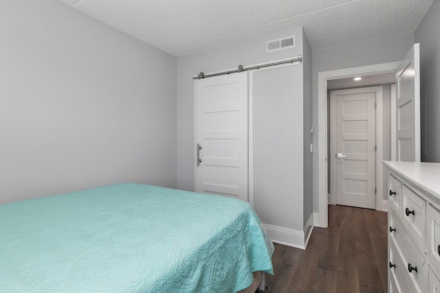 4210 N Natchez Ave Unit 208, Chicago, IL 60634 - bedroom with a barn door, dark wood finished floors, a textured ceiling, and a closet