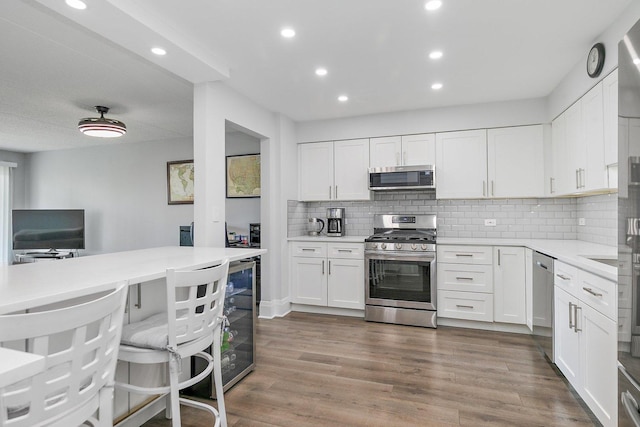4210 N Natchez Ave Unit 208, Chicago, IL 60634 - kitchen featuring appliances with stainless steel finishes, wine cooler, light countertops, tasteful backsplash, and recessed lighting