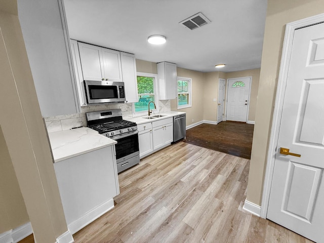 16802 Anthony Ave, Hazel Crest, IL 60429 - kitchen with appliances with stainless steel finishes, white cabinetry, light wood-type flooring, tasteful backsplash, and light stone countertops
