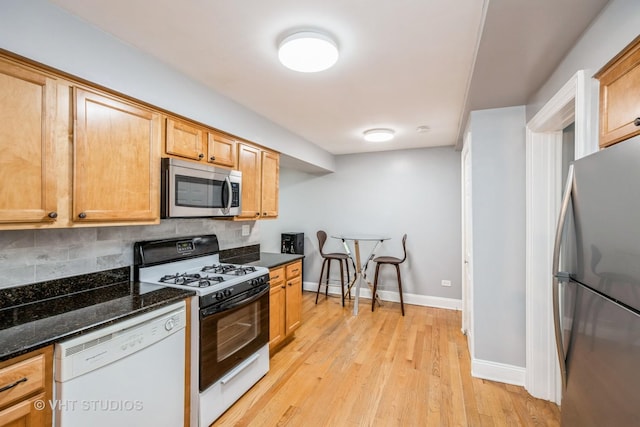 6255 S Mason Ave Unit 1B, Chicago, IL 60638 - kitchen featuring appliances with stainless steel finishes, tasteful backsplash, light wood-type flooring, and dark stone counters