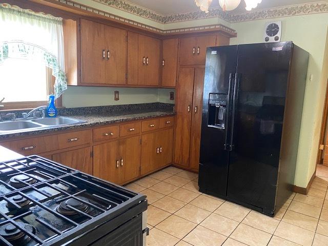 207 N Putnam St, Lostant, IL 61334 - kitchen with black appliances, brown cabinetry, light tile patterned floors, and dark countertops