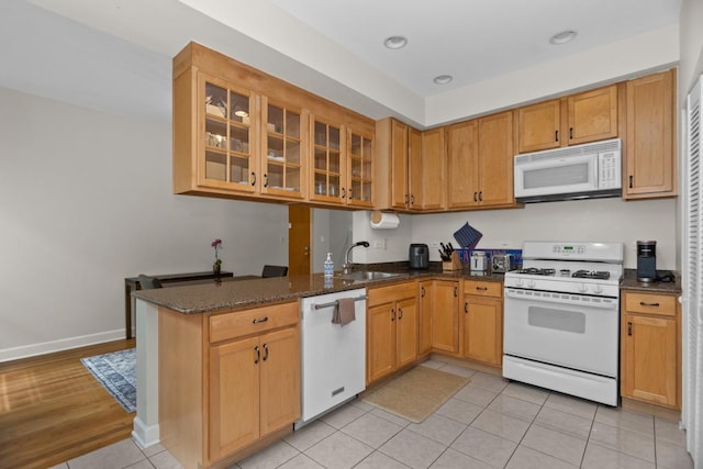 555 Elmwood Ave Unit 1, Evanston, IL 60202 - kitchen with white appliances, dark stone counters, light tile patterned floors, and glass insert cabinets