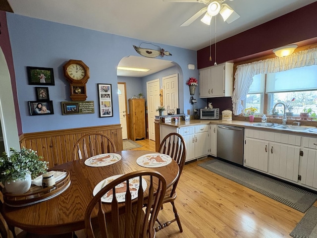 1112 W Wilmington-Peotone Rd, Peotone, IL 60468 - kitchen with stainless steel dishwasher, light wood-type flooring, wainscoting, arched walkways, and white cabinets