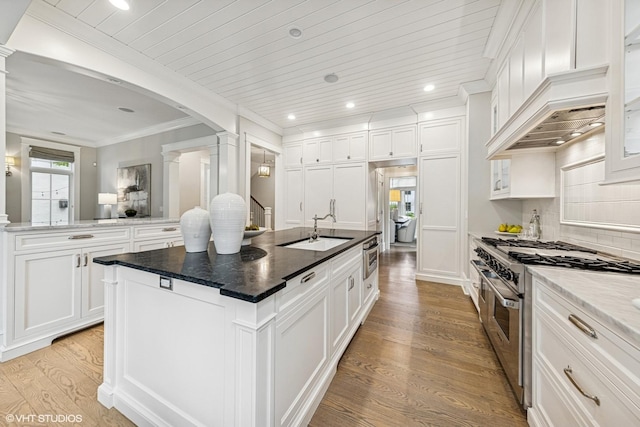 606 S Washington St, Hinsdale, IL 60521 - kitchen featuring high end stainless steel range oven, decorative columns, light wood-style flooring, an island with sink, and white cabinets