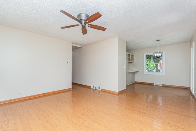 741 Gates St, West Chicago, IL 60185 - unfurnished living room featuring wood finished floors, a chandelier, ceiling fan, and a textured ceiling