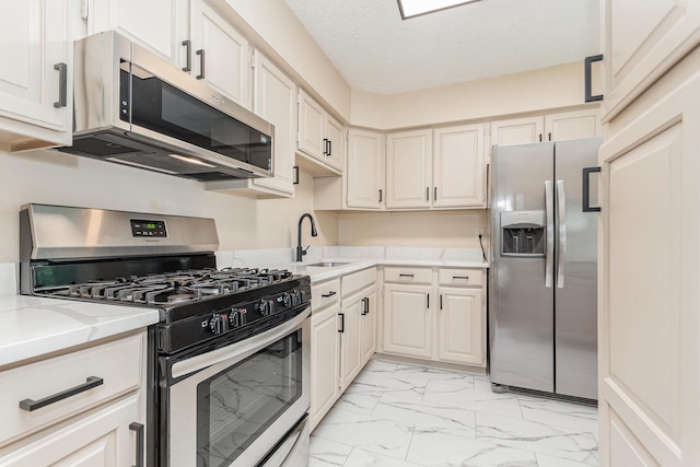 741 Gates St, West Chicago, IL 60185 - kitchen with appliances with stainless steel finishes, light marble finish floors, light stone countertops, white cabinetry, and a textured ceiling