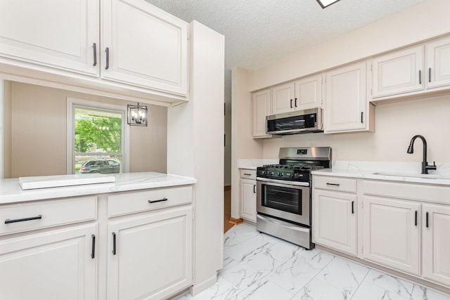 741 Gates St, West Chicago, IL 60185 - kitchen with appliances with stainless steel finishes, light marble finish floors, white cabinetry, a textured ceiling, and light stone countertops
