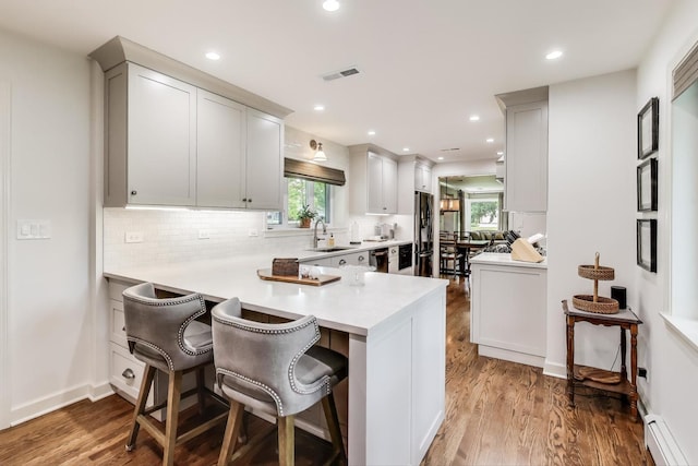 1311 E Woodford Pl, Arlington Heights, IL 60004 - kitchen with baseboard heating, wood finished floors, stainless steel appliances, a peninsula, and healthy amount of natural light