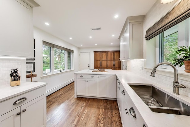 1311 E Woodford Pl, Arlington Heights, IL 60004 - kitchen featuring light wood finished floors, tasteful backsplash, a baseboard heating unit, a peninsula, and white cabinets