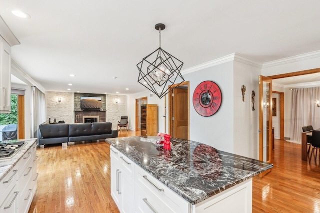 318 10th St, Wheeling, IL 60090 - kitchen with light wood-style floors, a fireplace, a kitchen island, dark stone countertops, and ornamental molding