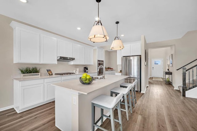 311 Snowdrop Ln, Elgin, IL 60124 - kitchen with stainless steel appliances, wood finished floors, a center island with sink, a kitchen breakfast bar, and light countertops