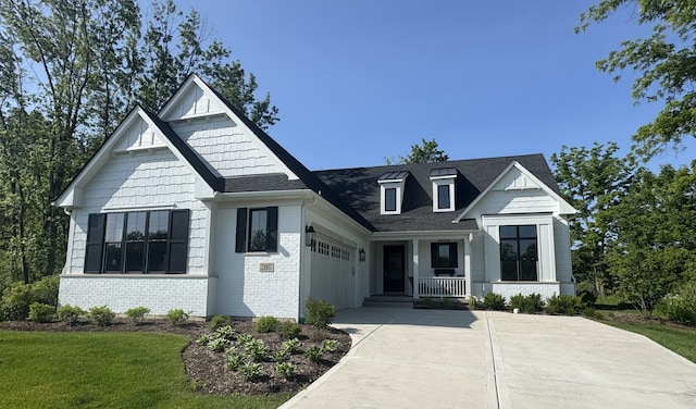 modern inspired farmhouse with a porch, concrete driveway, a garage, a shingled roof, and brick siding