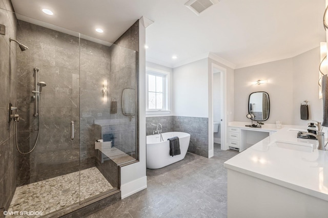 full bathroom featuring a stall shower, double vanity, a freestanding bath, ornamental molding, and recessed lighting