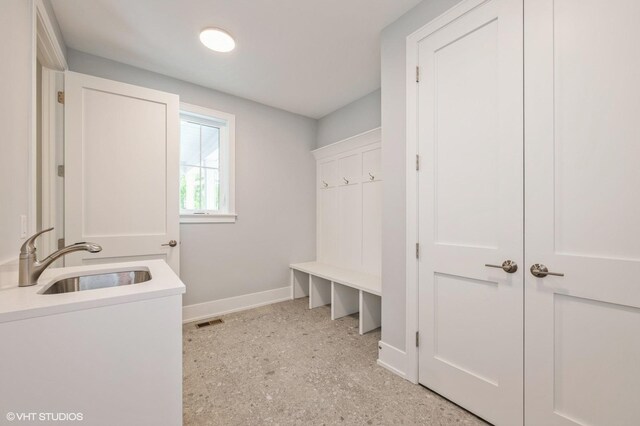 mudroom with a sink and baseboards