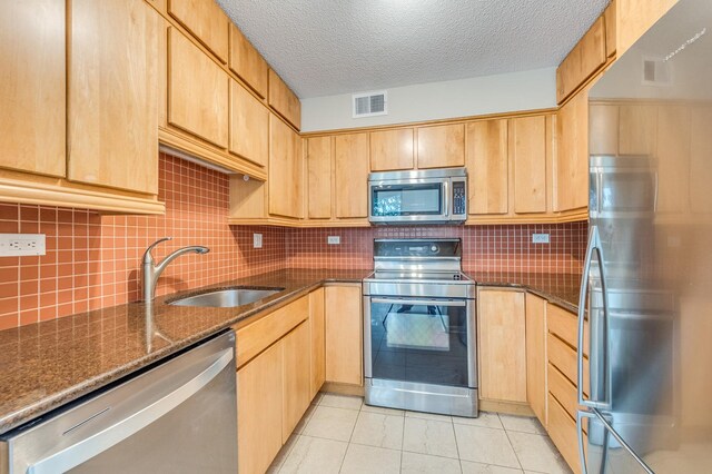 511 Aurora Ave Unit 410, Naperville, IL 60540 - kitchen featuring appliances with stainless steel finishes, light brown cabinets, dark stone countertops, light tile patterned flooring, and decorative backsplash