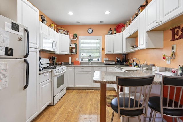 2602 Michael St, Wonder Lake, IL 60097 - kitchen featuring white appliances, a peninsula, open shelves, a breakfast bar, and white cabinetry