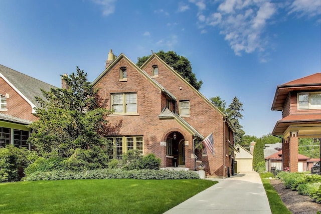 934 Jackson Ave, River Forest, IL 60305 - tudor house featuring a front yard, an outbuilding, brick siding, a detached garage, and a chimney