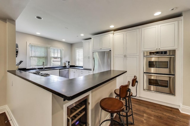 934 Jackson Ave, River Forest, IL 60305 - kitchen featuring appliances with stainless steel finishes, beverage cooler, dark countertops, white cabinetry, and recessed lighting
