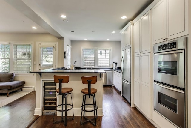 934 Jackson Ave, River Forest, IL 60305 - kitchen featuring appliances with stainless steel finishes, wine cooler, dark countertops, a kitchen bar, and dark wood finished floors