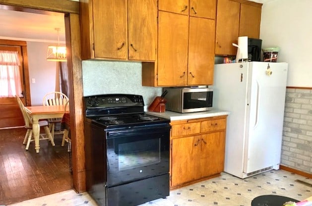 17218 Lincoln Rd, Morrison, IL 61270 - kitchen featuring black / electric stove, freestanding refrigerator, stainless steel microwave, light countertops, and brown cabinetry