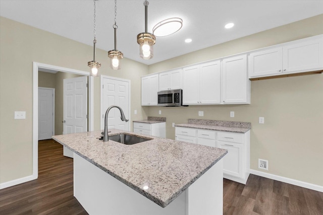 5 Montclair Rd Unit A, Urbana, IL 61801 - kitchen featuring stainless steel microwave, white cabinetry, dark wood finished floors, light stone countertops, and an island with sink