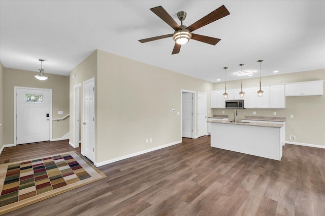 5 Montclair Rd Unit A, Urbana, IL 61801 - kitchen featuring stainless steel microwave, white cabinetry, dark wood-style floors, a center island with sink, and ceiling fan