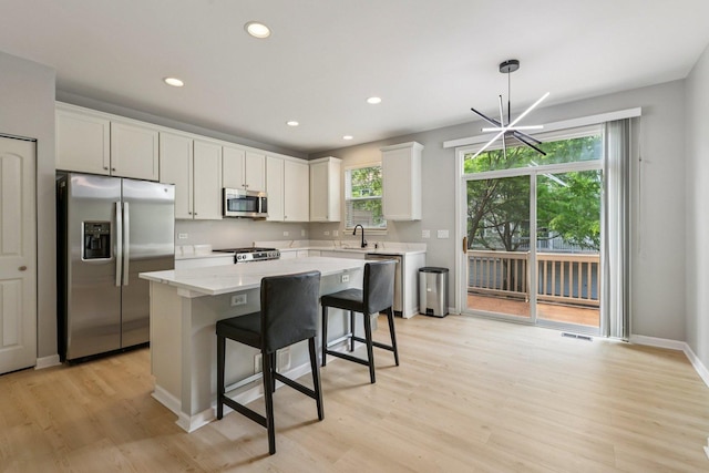 5608 Cambridge Way, Hanover Park, IL 60133 - kitchen with appliances with stainless steel finishes, light wood-style flooring, a kitchen island, a kitchen bar, and white cabinets