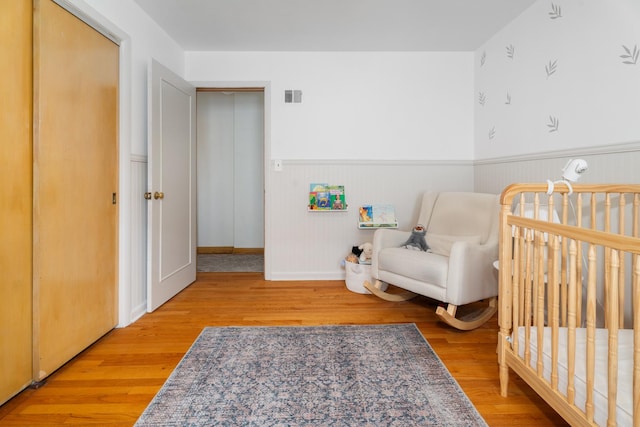 5660 N Rogers Ave, Chicago, IL 60646 - bedroom featuring wainscoting, wood finished floors, and a nursery area