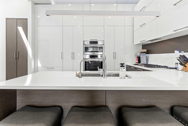 1420 W Fulton St, Chicago, IL 60607 - kitchen featuring modern cabinets, appliances with stainless steel finishes, white cabinetry, and a kitchen breakfast bar