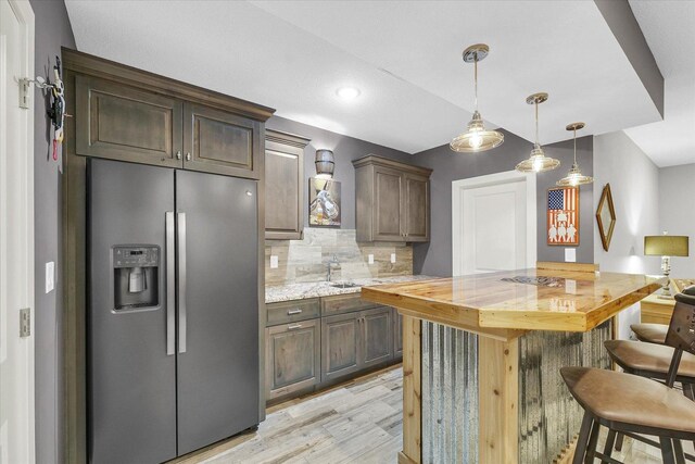 619 County Road 2550 N, Dewey, IL 61840 - kitchen with stainless steel fridge with ice dispenser, light wood-type flooring, a breakfast bar area, backsplash, and pendant lighting