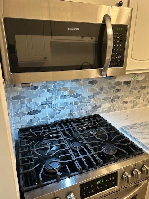 2149 Country Club Dr Unit 16, Woodridge, IL 60517 - kitchen view of stainless steel appliances, backsplash, white cabinetry, and light stone countertops