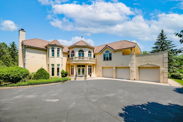 W3318 Lake Forest Ln, Lake Geneva, WI 53147 - mediterranean / spanish home featuring french doors, a balcony, driveway, a tiled roof, and a chimney