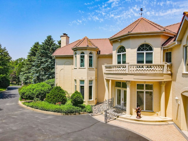 W3318 Lake Forest Ln, Lake Geneva, WI 53147 - back of house with french doors, a balcony, a chimney, a tiled roof, and stucco siding