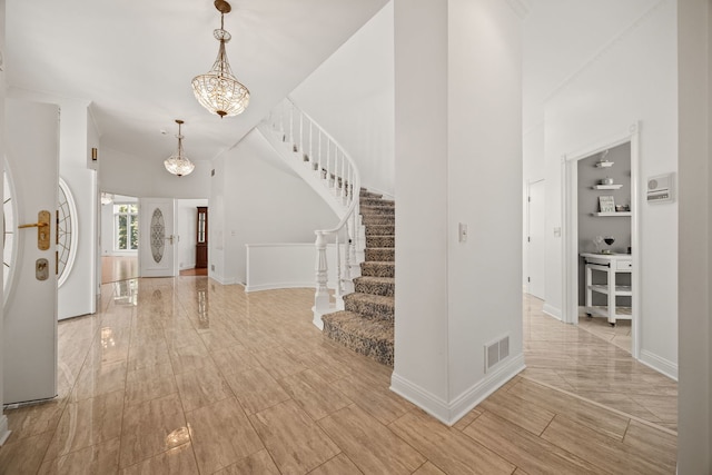 W3318 Lake Forest Ln, Lake Geneva, WI 53147 - entrance foyer featuring stairway, a chandelier, wood tiled floors, and a towering ceiling
